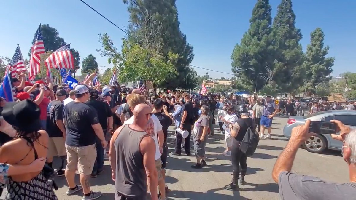 Backup (left) was only PRETENDING to deescalate.Cast Lady goes back on the attack.Target had his back to her, his hands raised in the heavy metal hand sign.