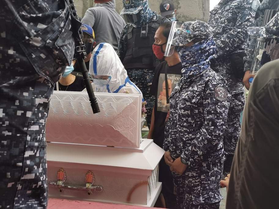 LOOK: Nasino, cuffed, wearing a full PPE set, and flanked by cops, gazes at her daughter River for the final time at the Manila North Cemetery. (: Kapatid) |  @MBMinkaTiangco