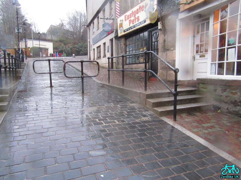 One footway was lost when it was replaced with stone cubicles used informally as alfresco extensions for the businesses opposite. A new, short flight of three steps was introduced into the footway in front of the businesses. The bollards were replaced by two offset barriers. 2/7
