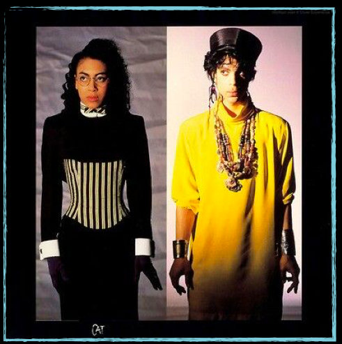 Prince & Cat mirror each others poses with Prince’s silhouette highlighted in yellow, his body unusually not tailored. His metal cuffs mimic Cat’s wrists and his defined curls falls from beneath his cap. P often styled women in similar ambiguous manner.