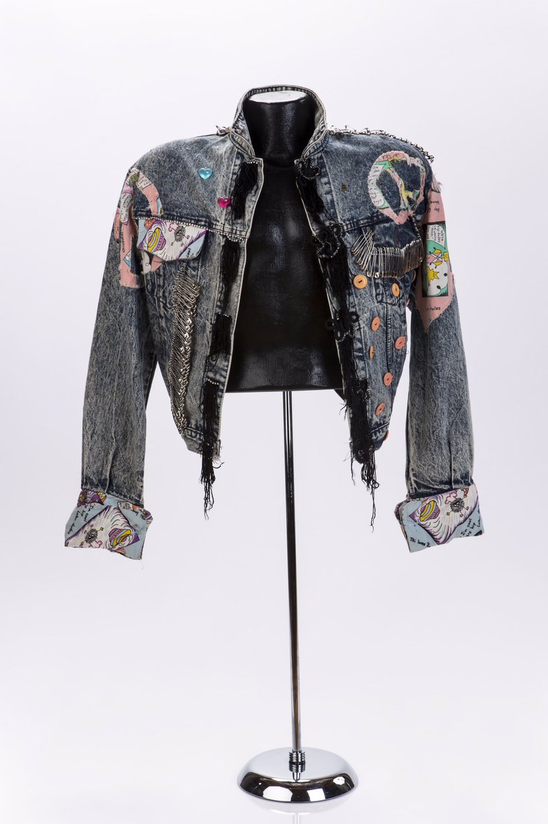 Dark acid-wash denim with upturned collar & boxy silhouette exaggerated w/ stacked shoulder pads, a P signature. The jacket is DIY’d w/ fringe, rhinestone trim, glass heart beads, peach buttons stitched in black & fabric appliqués.