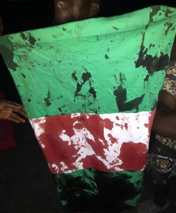 _McOatt's tweet photo. “They won’t shoot at the flag” they said 

7 down, according to the news making the rounds. @jidesanwoolu this is totally on you, all of these blood will speak against you. Don’t worry. 

#EndSARS #EndPoliceBrutalityinNigeraNOW #EndSARSImmediately https://t.co/yZkx5oI9Fm
