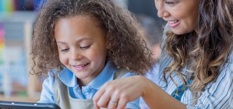 child and adult smiling while watching on a tablet