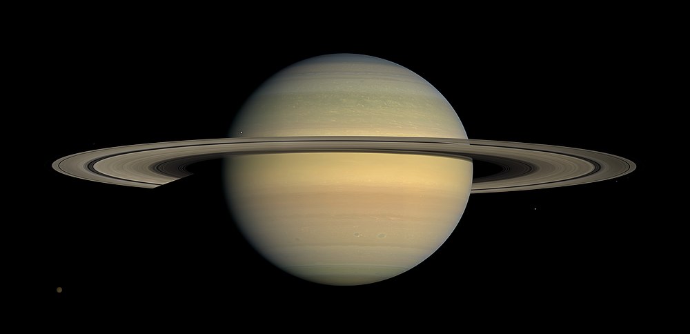 This natural-color mosaic image was taken by the Cassini orbiter. As it panned its wide-angle camera across Saturn and its ring system as the planet approached equinox. Six moons are pictured in the panorama, with the largest, Titan, visible at the bottom left.