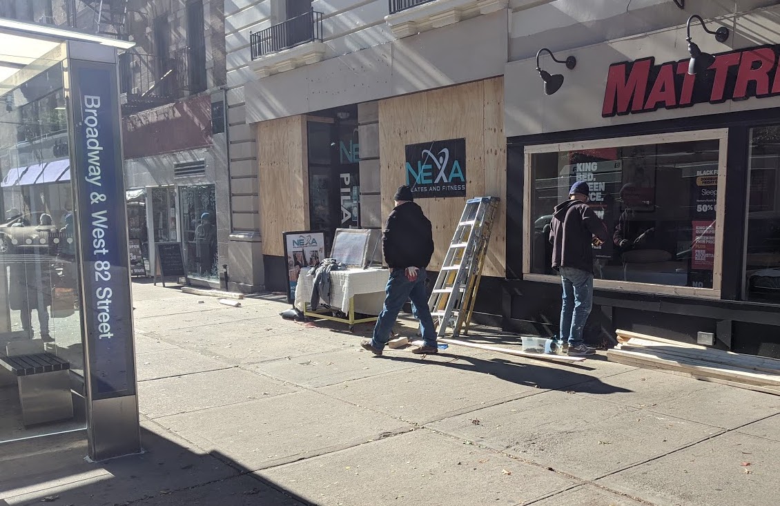 Workers at Broadway and 82nd Street in NYC board up shop windows to protect them in case of post-election violence.