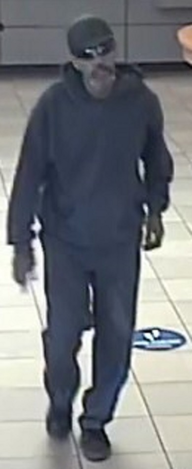 Man wearing a black baseball hat, black sweatshirt and black pants.