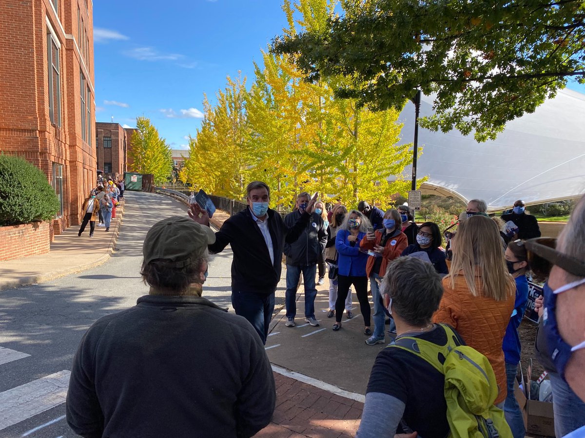 Sen. Mark Warner addresses a crowd of people outdoors. Everyone is wearing a face mask.
