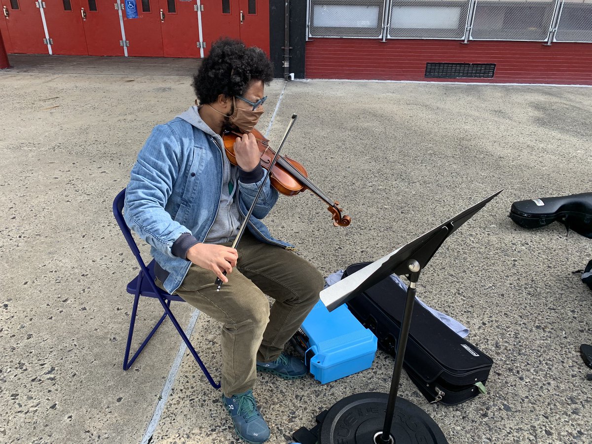 Carlos Santiago tunes his violin as at least a dozen spectators and voters at South Philadelphia High School look on. Santiago is part of a string quartet that performs regularly around Philadelphia.