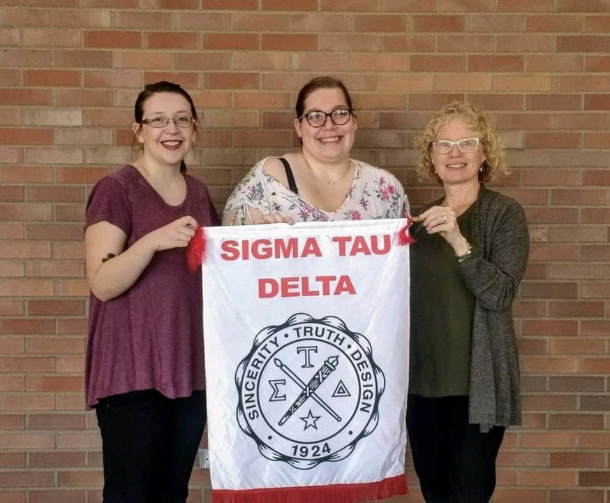 SigmaTauDeltaVU's tweet image. Former and current members, Courtney and Jessica, hold up the Sigma Tau Delta flag alongside Sigma Tau Advisor, Professor Elizabeth Burow-Flak. 

4 more days until we meet our new members!! 💗📝

#SincerityTruthDesign