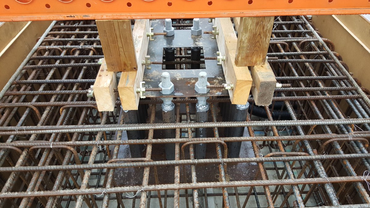 Holding-down bolts are fixed into the pile-cap, this will bolt the metal structure to the concrete, pilecap is then cast and you have a huge block of concrete as in pic. Pilecaps can sometimes be buried but most are above ground as it protects steelwork from impact 16/
