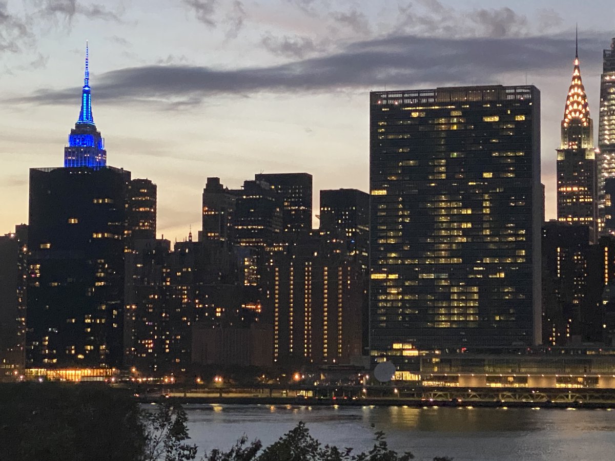 Empire State Building lit up in UN Blue with the UN Building on the right. 