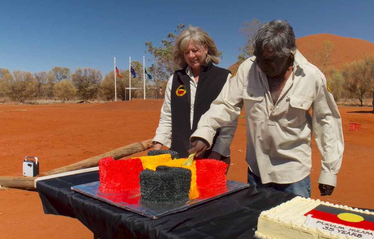 UluruTV's tweet photo. 26 Oct 2020: Celebrations at Uluru today, exactly one year since the climb was closed and 35 years since "Handback". Chairman, Sidney James - with Park Manager Dianne Scopel - cuts the cake. @sussanley @Parks_Australia @ulurustatement @MarukuArts https://t.co/8z7Pst8Sd9