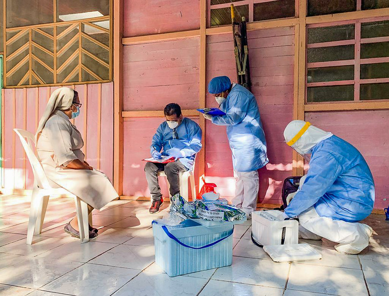People wearing masks and lab coats writing on clipboards. 