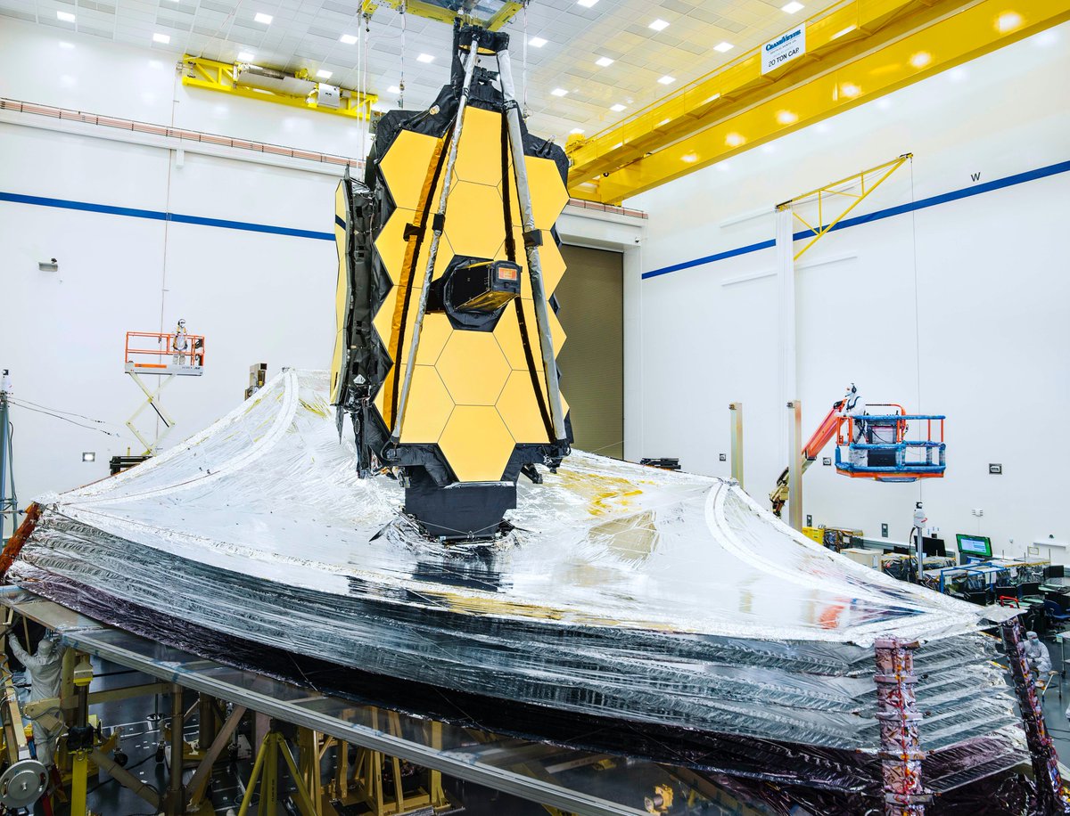 The James Webb Space Telescope with its fully extended sunshield. A technician in a cleanroom suit is on the right.
