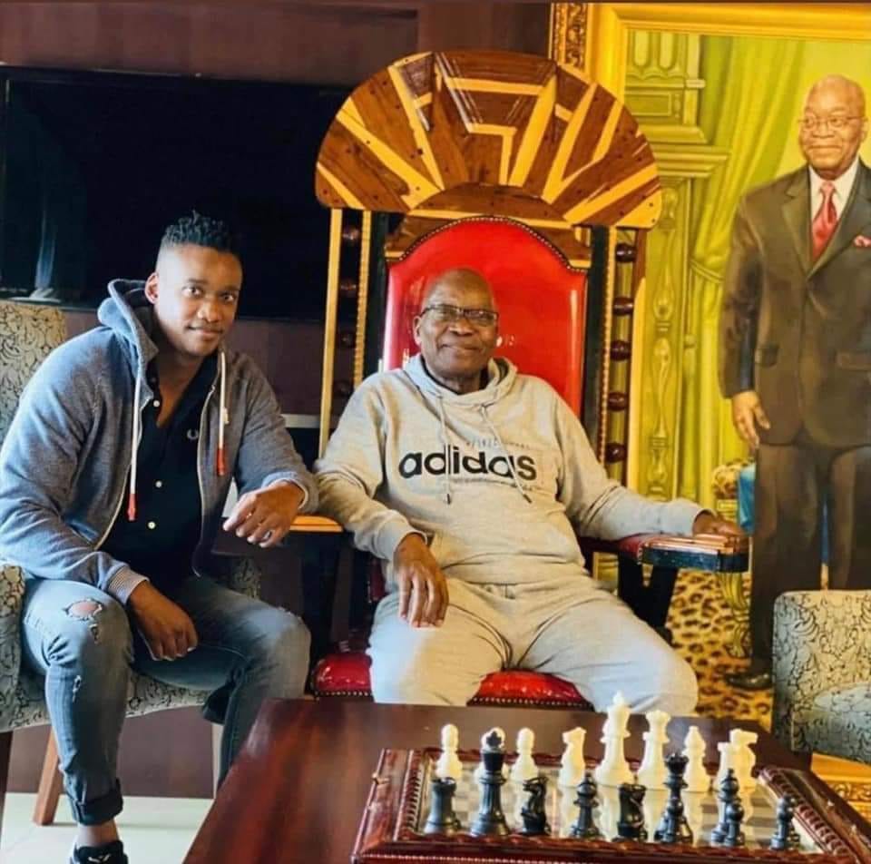 TheTokenut's tweet photo. So much to love about this photo. The wannabe African dictator throne JZ is seated on. The slightly better than Rasta portrait smugly grinning down at them. The Adidas swag. The torn jeans. But I think my fave, is the chess board. #leadership #JacobZuma #duduzanezuma #zuma #swag https://t.co/l76EOnwkh3
