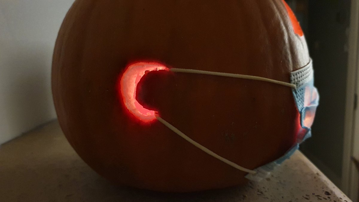 Carved pumpkin with a mask, elastic around its ears