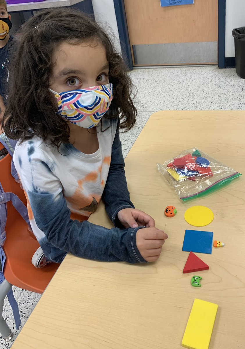 krista_booth's tweet photo. Shapes, prepositions, and Halloween fun all at once! Place the pumpkin below the shape with no vertices, place the candy corn above the shape with 4 equal sides, place the cat beside the shape with 3 vertices.....what shape left? Describe it! @TrantwoodES https://t.co/ZtnOUQSSNF