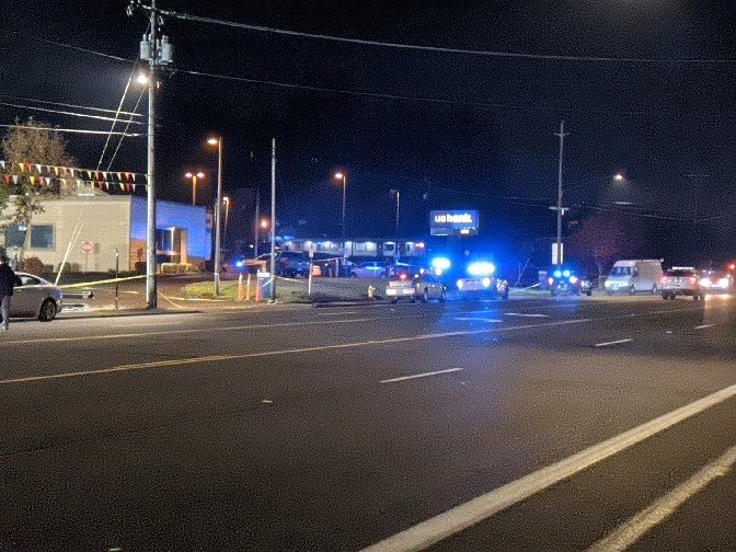 A us bank parking lot across the street with some cop cars in front of it.