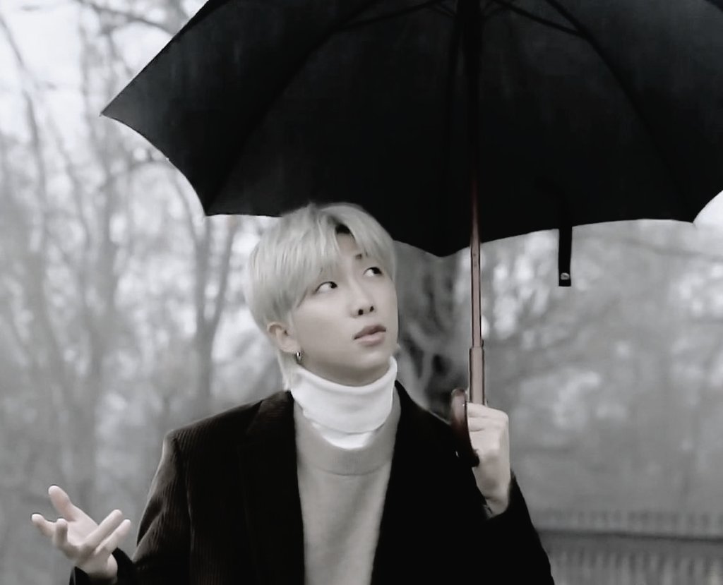 Joon is asking the falling rain to conceal his sorrowful tears by pouring on him the first time he says this, the next time is perhaps implying how he wishes his misery to be washed away completely by the falling rain which he considers his friend, that comes to him now n then