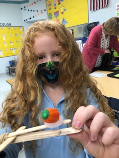 MTCESK8's tweet photo. There are some budding engineers in Mrs. Frame's first grade class. They have been working hard on designing and building small catapults using plastic lids, wooden sticks, and rubber bands. They used them to launch candy pumpkins. #mtcesSTEAM #HalloweenIsComing https://t.co/saBWXhkV1K