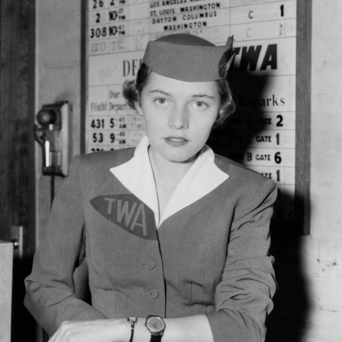 A 1956 black-and-white photograph showing a TWA flight attendant at then-Friendship International Airport wearing 2 watches in preparation of the ending of daylight saving time.