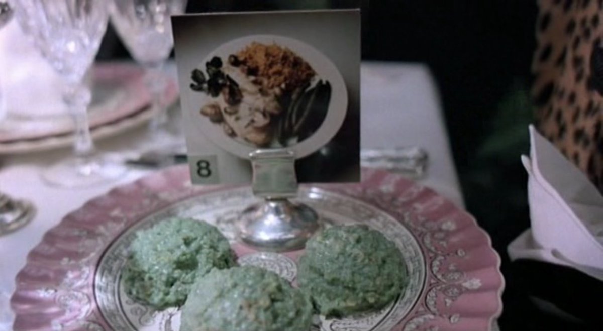 Still from the movie "Brazil" of green goop on a plate, with a photo of a delicious meal above it