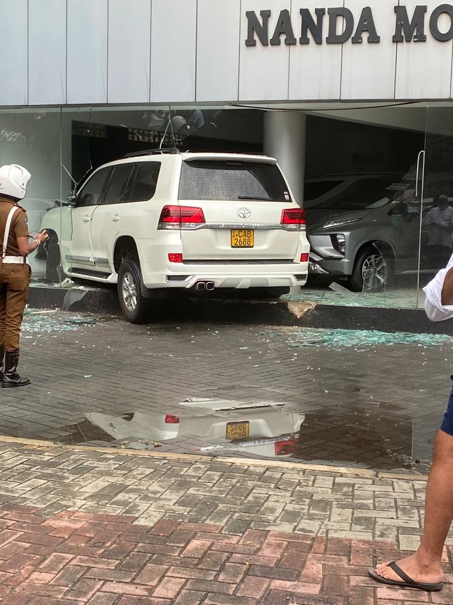 rangaba's tweet photo. A woman driver crashed a Toyota Land Cruiser into Nanda Motors, smashing the showroom and two brandnew vehicles. Errant driver is said to be a daughter of a senior police officer whose other son had killed a traffic police inspector in a hit-and-run incident in March last year. https://t.co/XVx3UBDTOp