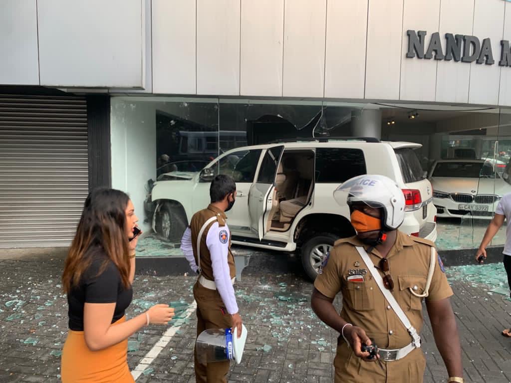 rangaba's tweet photo. A woman driver crashed a Toyota Land Cruiser into Nanda Motors, smashing the showroom and two brandnew vehicles. Errant driver is said to be a daughter of a senior police officer whose other son had killed a traffic police inspector in a hit-and-run incident in March last year. https://t.co/XVx3UBDTOp