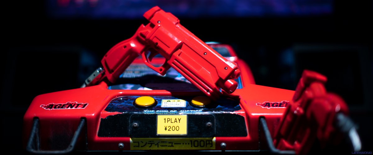 Photography by Liam Wong of Japan at night. A close-up of the iconic red plastic gun for a SEGA arcade.