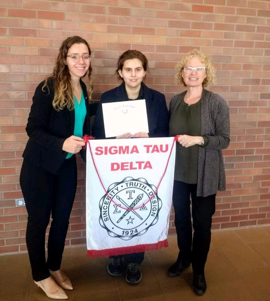 SigmaTauDeltaVU's tweet image. Former and current members, Emily and Jewel, hold up the Sigma Tau Delta flag alongside Sigma Tau Advisor, Professor Elizabeth Burow-Flak. 

3 more days until we meet our new members!! 💗📝

#SincerityTruthDesign