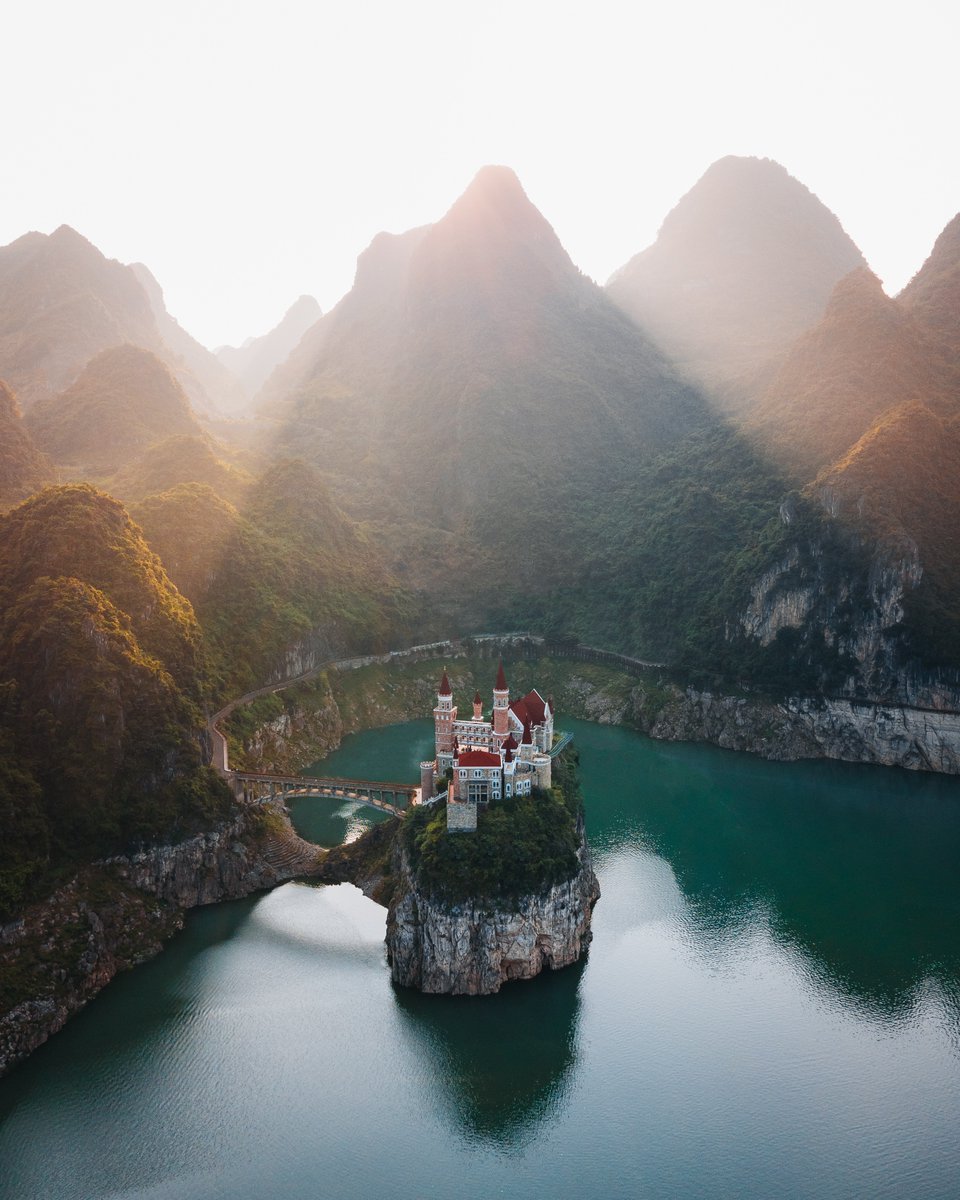 Discovery's tweet photo. In rural southwestern China sits a Bavarian-style castle on a lake, surrounded by mountains. 
  
Photo + Caption: Kelsey Johnson (@heykelseyj/IG) https://t.co/ifm6VSt3bi