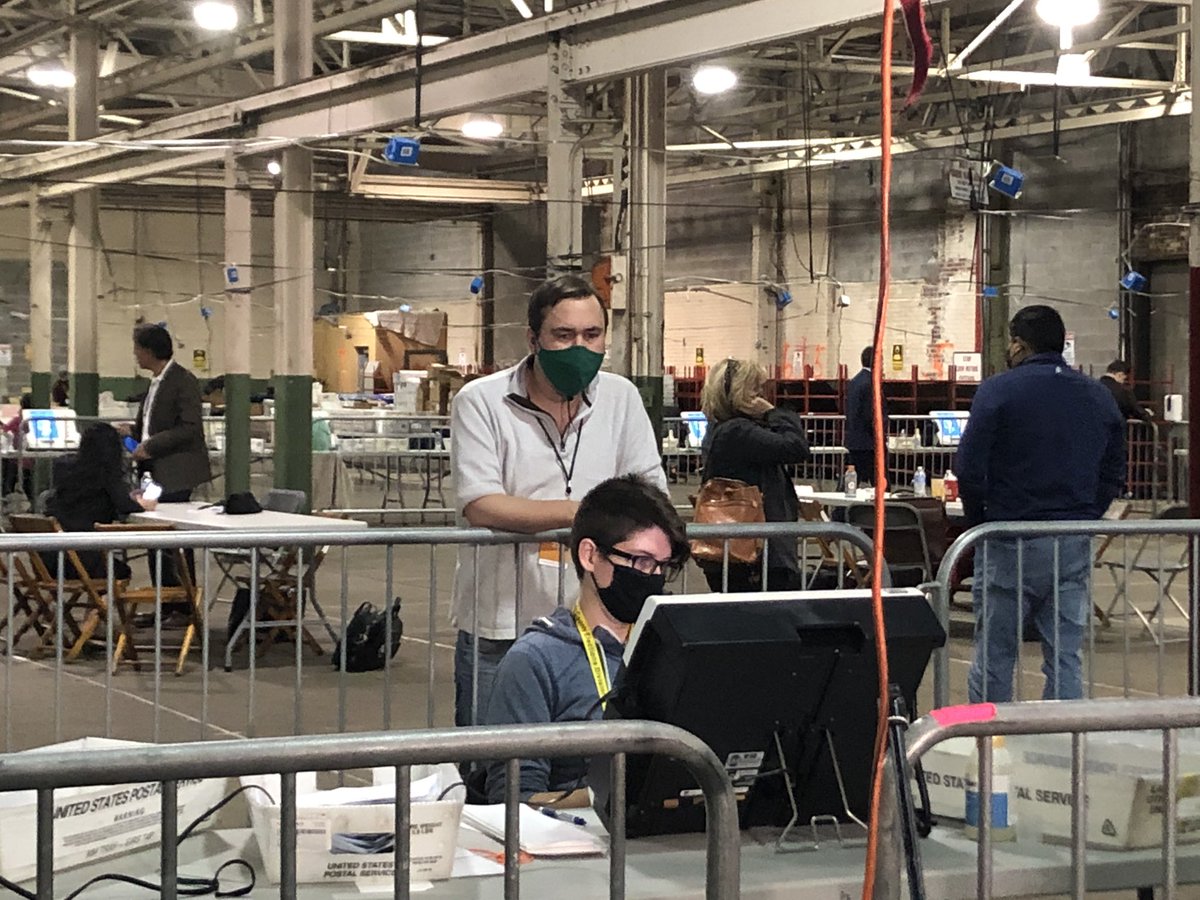 An observer looks over the shoulder of a poll worker