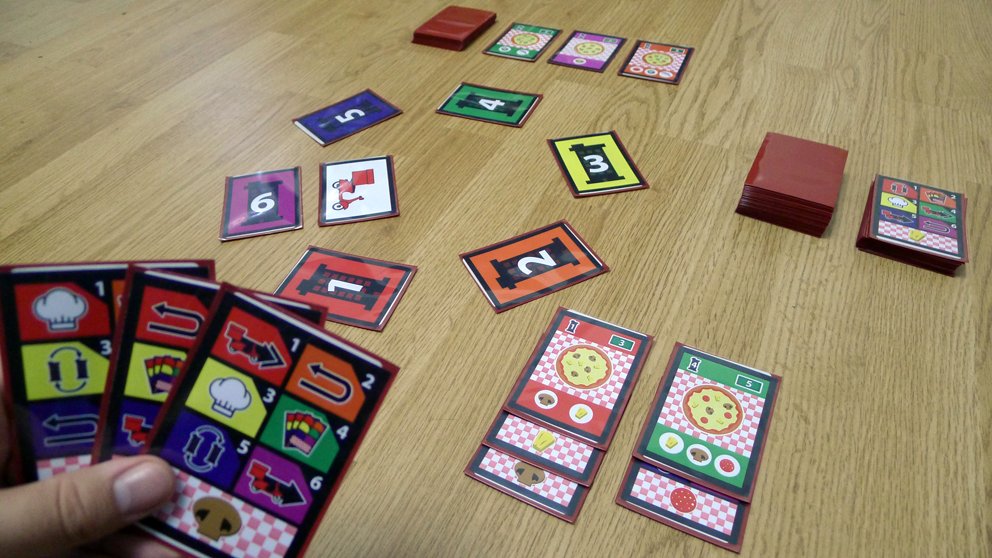 Delivering mail was fun but too quick. Players could do it on the same turn. I wanted something they would have to prepare and then deliver, so food felt intuitive.Pizzas are so modular, they felt perfect for this new version. I changed its name to Pizza-go-round.