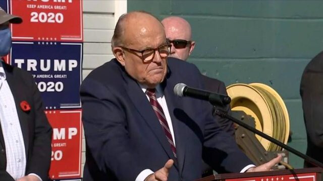 MichaelFeasey1's tweet photo. Rudy Guiliani, next to a garden hose, saying the president will not concede. He is at the Four Seasons Total Landscaping company between a porn store and a funeral parlour in Philadephia because the campaign accidentally booked this venue instead of the Four Seasons hotel!     🤣 https://t.co/GkeWu25ViJ