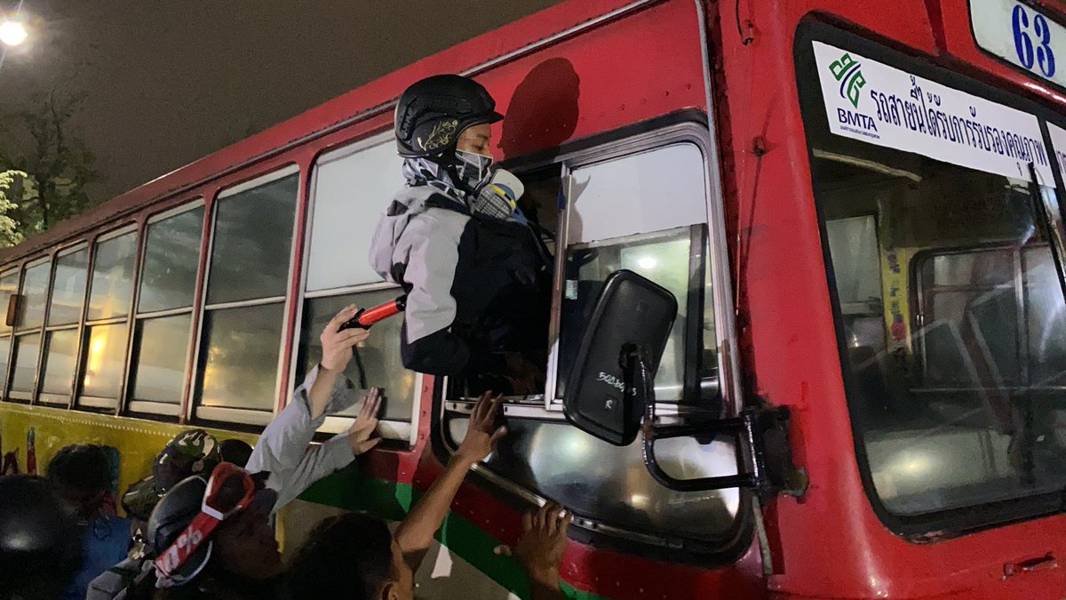A volunteer guard climbed into a bus/barrier so he can move it with the first view of the water cannon trucks behinds it.  #ม็อบ8พฤศจิกา