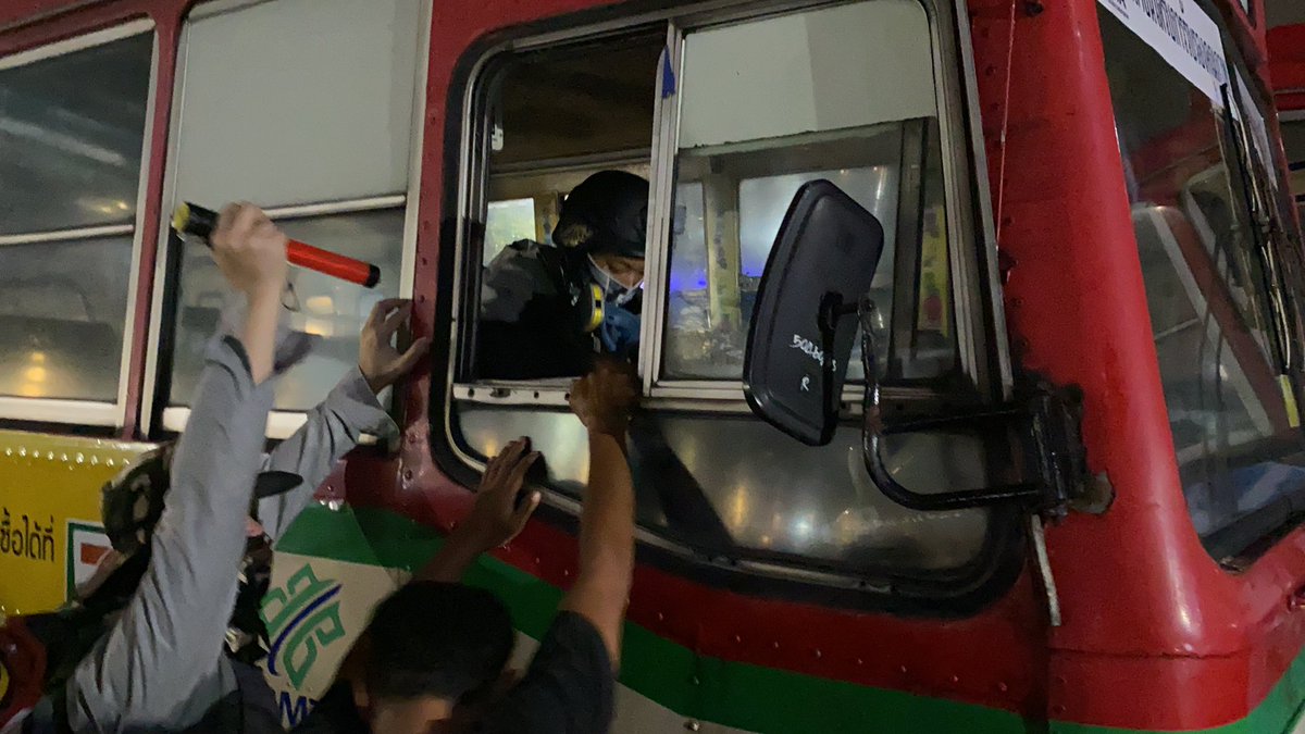 A volunteer guard climbed into a bus/barrier so he can move it with the first view of the water cannon trucks behinds it.  #ม็อบ8พฤศจิกา