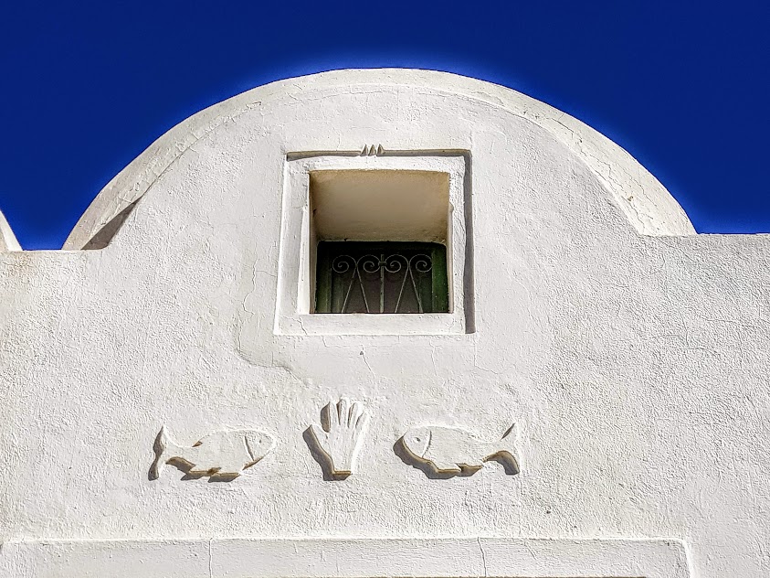 1) In Tunisia, if you look closely at details, you can find fish symbolism EVERYWHERE:Doors, jewelry, dresses, walls, windows, mosaics, songs, expressions "7outa 3lik" etc...Sometimes you can even find actual fish tails hanging around!Fish symbolizes fruitfulness and luck.