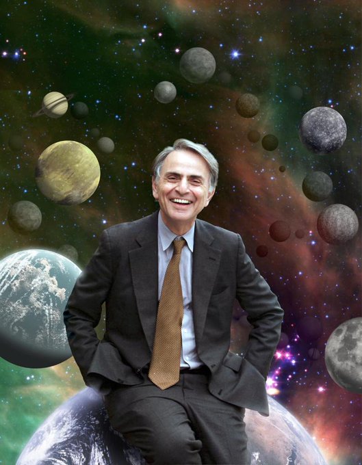 Photo of Carl Sagan in front of an outer-space themed background.