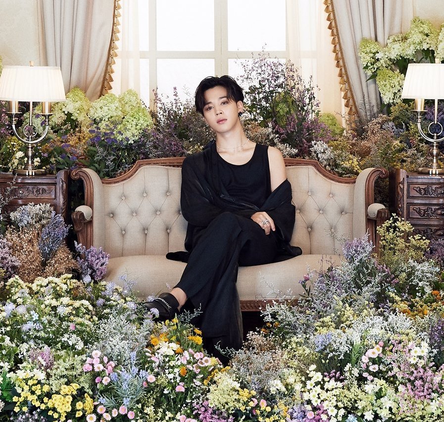 The couch Jimin is sitting on and side tables are modernized baroque, with floral ornaments, beautifully complemented by the real flowers surrounding him. The padding pattern on the couch, and its winged shape, are also typical of the baroque style (Versailles on the right). +