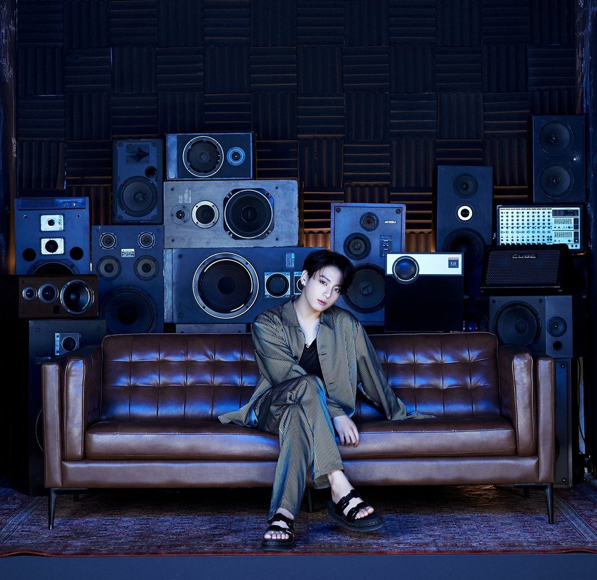 Jungkook chose a leather couch and a cozy rug to complement the industrial feel of his room. The leather couch is a prime element of the more masculine "man cave" industrial style. It's also a modern couch design, adding to the sleek look of the room. +