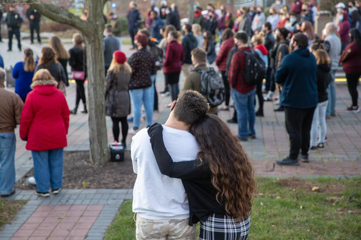 Students embracing with crowd in background.
