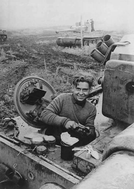 A happy Tiger driver slicing through bread, part of his daily cold rations.Typical example being;750g bread 120g sausage, preserved fish, tube cheese45g fat200g jam or ersatz honey7 cigarettes 2 cigars 1 roll of candyHis issued folding fork & spoon is bottom right.44)