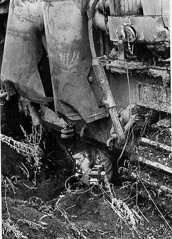 This Tiger commander uses his sleep pit/shelter to speak to another unit or units via a standard feldfernsprecher 33 (telephone). Connected to another phone or 10 line exchange, he’s clearly in a semi-permanent position to have such communication in place. Who to though?46)