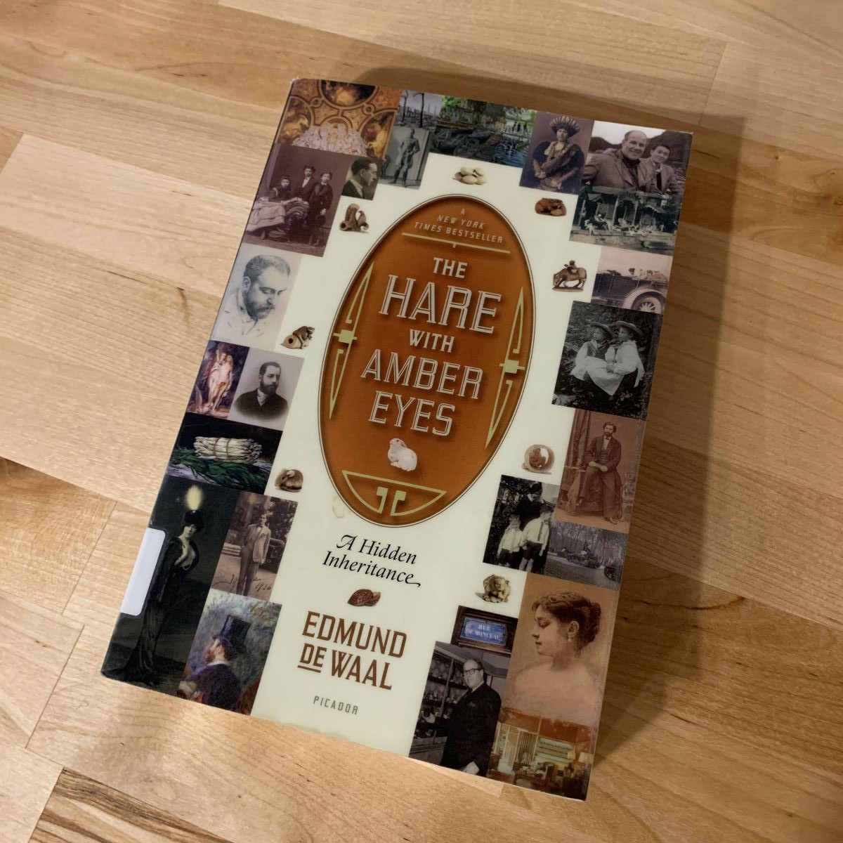 The book "The Hare with Amber Eyes" on a wooden surface.