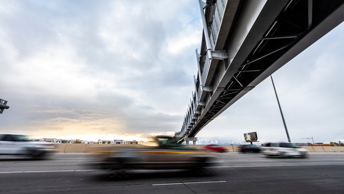 Pedestrian bridge spanning I-15 with cars zooming underneath.