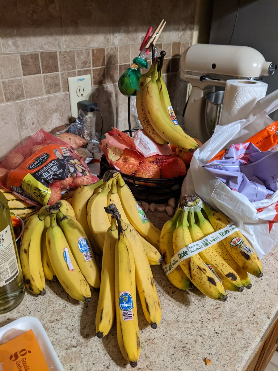 A kitchen counter with five bunches of bananas on it.