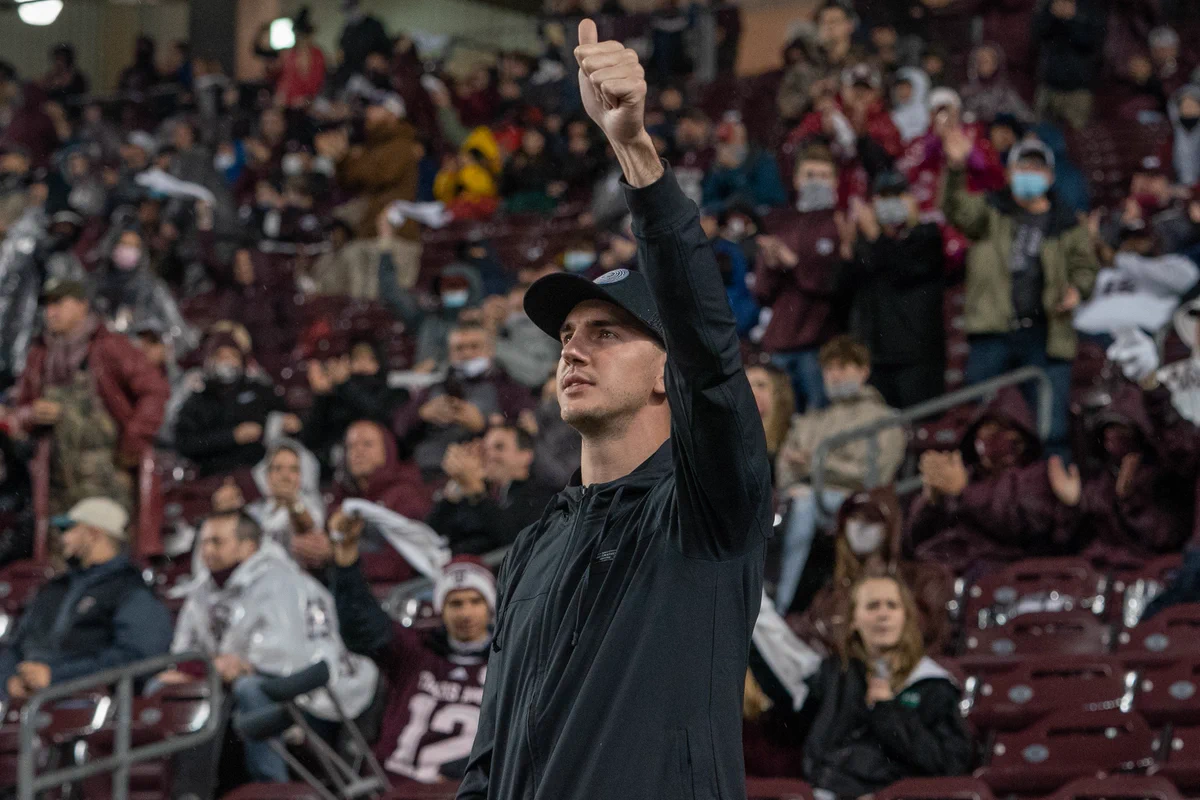 alex caruso holding a thumbs up in the air being recognized at kyle field