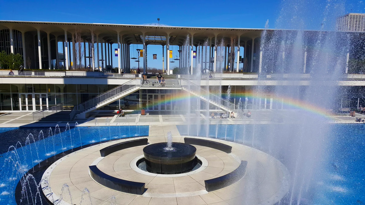Picture of the UAlbany fountain at the center of. campus with a rainbow going through the fountain. 
