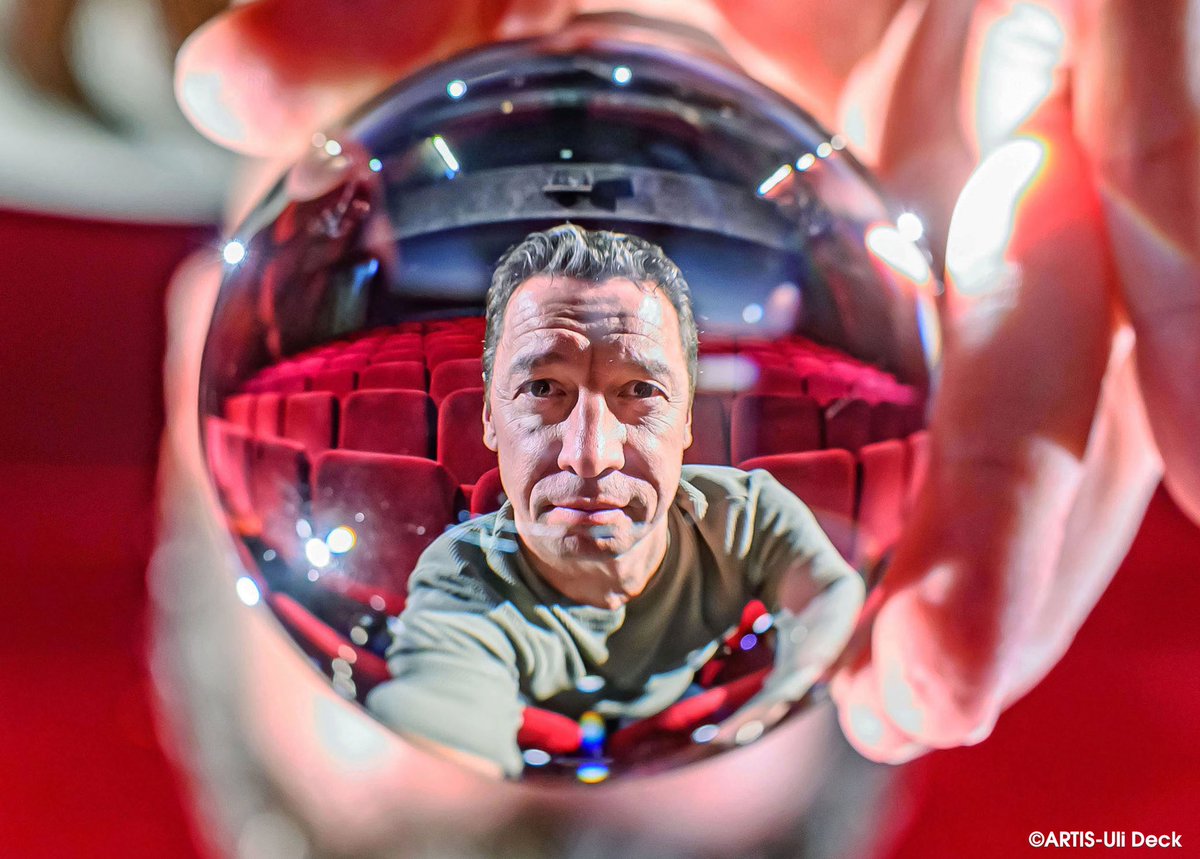 DER VISUELLE K(L)ICK - Kulturportrait in Zeiten von Corona -  Bernd Gnann, Geschäftsführer des Kammertheater Karlsruhe, sitzt im Zuschauerraum und blickt durch eine Glaskugel.  Foto Copyright: ARTIS-Uli Deck #kammertheater#karlsruhe#corona#lockdown#kultur#geschlossen#rot#