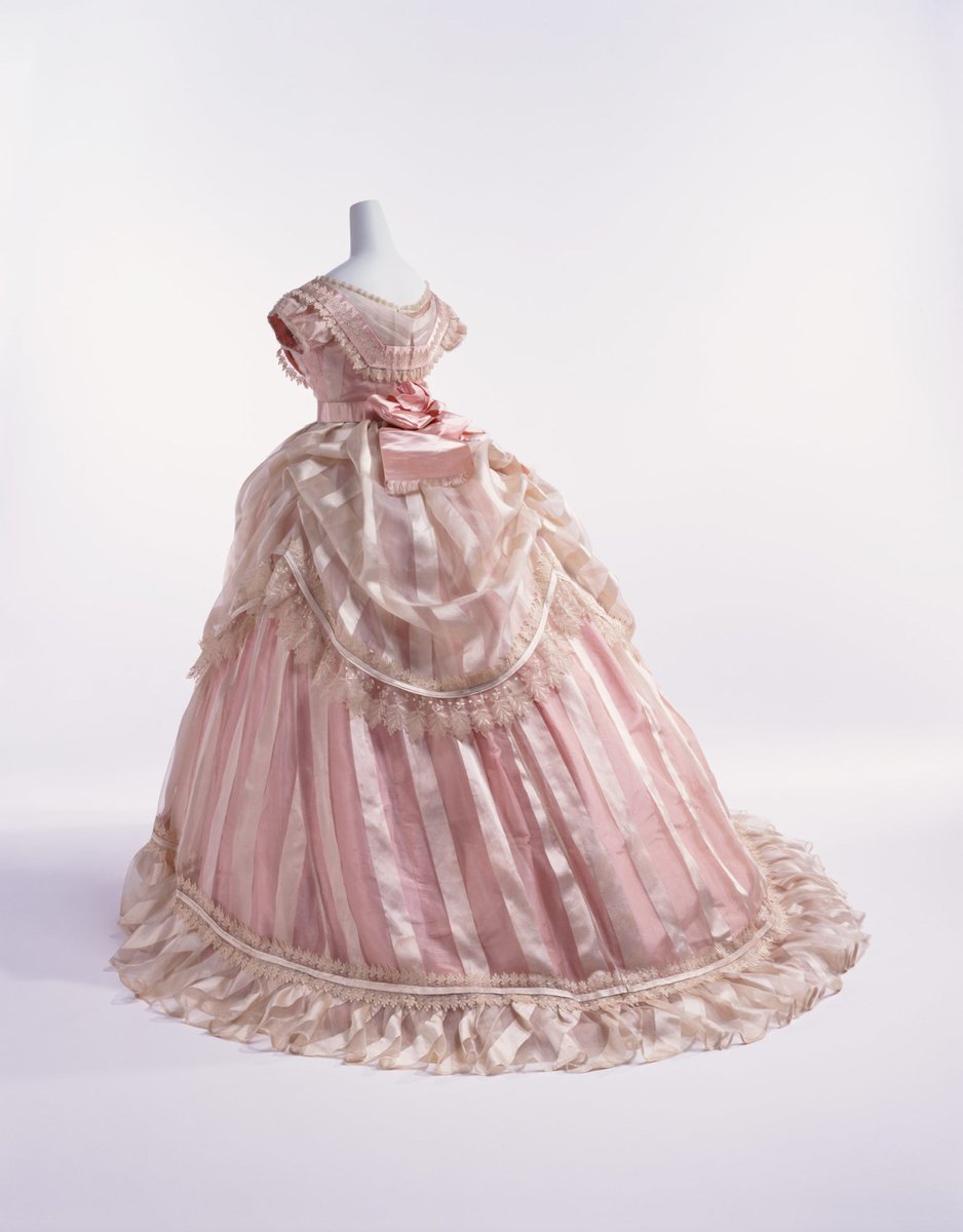 By 1868, the fullness of women's skirts had moved to the back, and a bustle was needed to support fashionable puffed overskirts and large sashes. The high back interest continued in the early 1870s as the bustle gradually swelled in size.